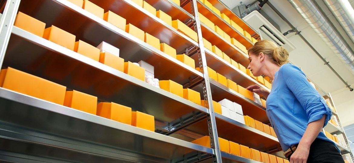 Female pharmacy employee searching shelves for drugs and medicin